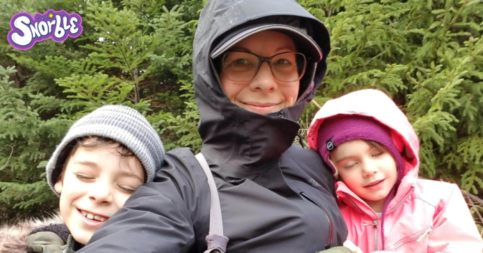 Image contains a photo of a woman, Dee Loft, in a raincoat in the center. On her right and left, there are two small children smiling with their eyes closed.