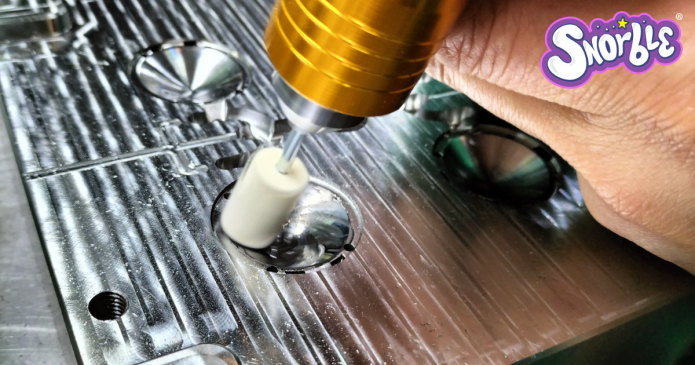 Image contains a photo of a polishing tool being used on a metal block.