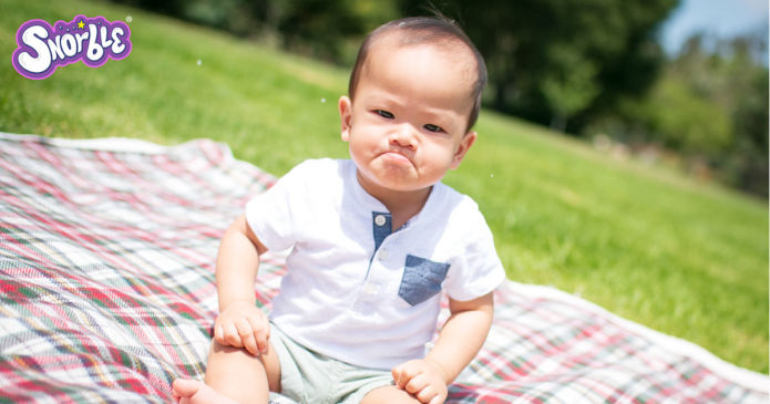 Image contains a photo of a toddler sitting on a blanket with a frown on their face.