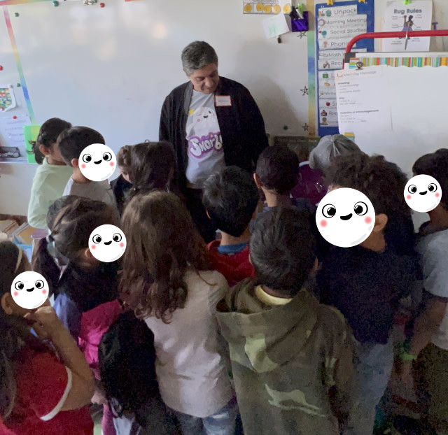Image contains a photo of a classroom with Snorble CEO, Mike Rizkalla, in the background wearing a Snorble tshirt and talking with a group of kids gathered closely together.