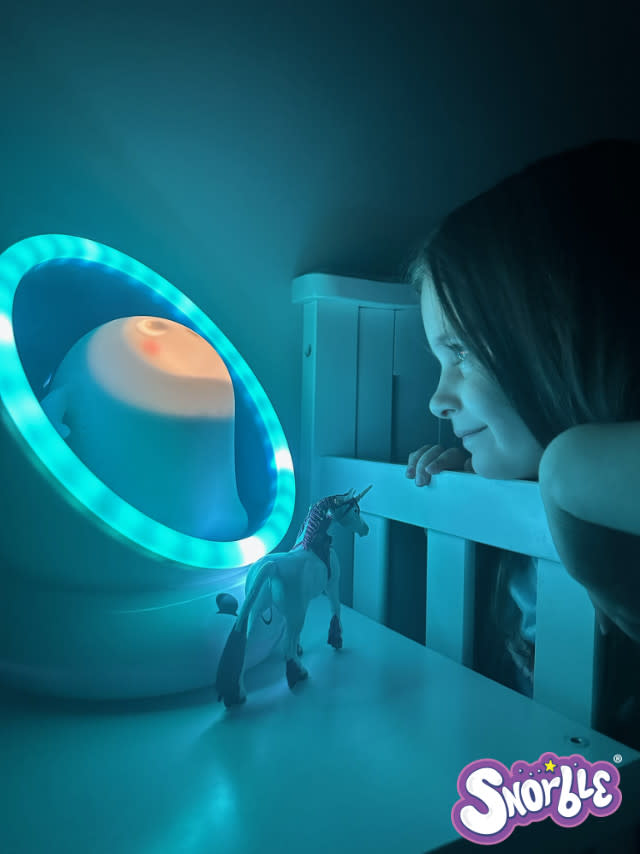 Child looking at Snorble® with love as Snorble's Lullapod glows.