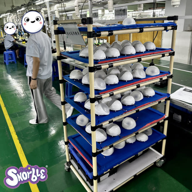 Factory workers stock a shelf of Snorble® parts.